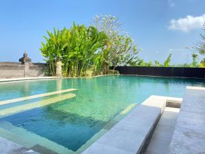 a swimming pool with turquoise water and trees at Medewi Surf Villa Luxury in Airsatang