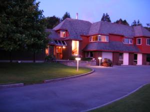 una gran casa roja con dos luces en la entrada en Woodland Glen Lodge B&B en Hokitika