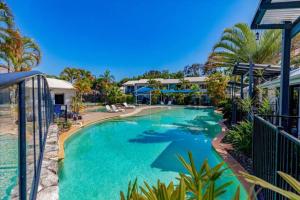 a swimming pool at a resort with palm trees at Noosa River Walk - Unit 107 in Noosaville