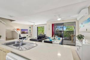 a kitchen with a sink and a living room at Noosa River Walk - Unit 107 in Noosaville