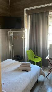 - une chambre avec un lit blanc et une chaise verte dans l'établissement PARAISO Da PENHA, à Lisbonne