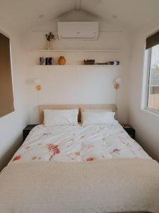 a bed in a small room with a white bedspread at Little Lodge - Luxury Tiny Home Stay in Alstonville