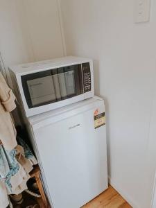 a microwave sitting on top of a refrigerator at Little Lodge - Luxury Tiny Home Stay in Alstonville