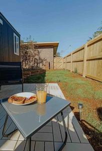 a table with a pizza and a glass of orange juice at Little Lodge - Luxury Tiny Home Stay in Alstonville