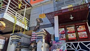 un frente de tienda con una estatua de un perro encima de los libros en Gustav Bali Homestay and Massage, en Sanur