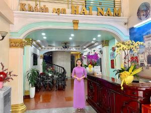 胡志明市的住宿－Hải Nam Hotel (Sài Gòn)，站在大厅的身着紫色衣服的女人