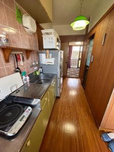 een kleine keuken met een wastafel en een fornuis bij 民宿ちねん in Uruma