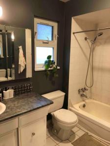 a bathroom with a toilet and a tub and a sink at private room with queen bed in richmond 202 in Richmond