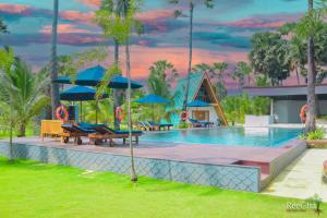 una piscina en un complejo con sombrillas azules en Reecha Organic Resort Jaffna en Kilinochchi