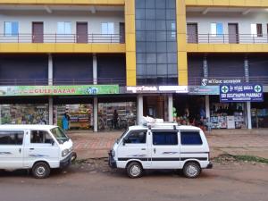 two white vehicles parked in front of a building at Paadi Inn in Kakkabe