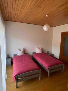 duas camas num quarto com lençóis vermelhos em Gîte Le p’tit Mintz em Natzwiller