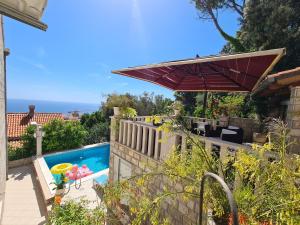 a house with a swimming pool and an umbrella at Guesthouse Villa Klaic in Dubrovnik