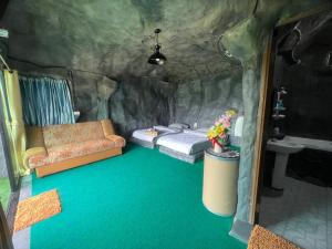 a room with two beds and a couch in a cave at สวนป่าภูนับดาว รีสอร์ท เขาค้อ in Ban Khao Ya Nua