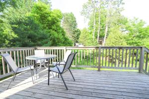 un patio con mesa y sillas en una terraza de madera en 23Maple en Haliburton