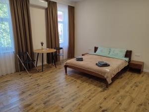 a bedroom with a bed and a table and windows at SweetHomeApartment in Kamianets-Podilskyi