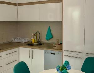 uma cozinha com armários brancos e cadeiras verdes em Filip Apartment em Mavrovo