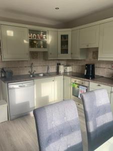 a kitchen with white cabinets and a chair in it at Cosy home in Dungarvan