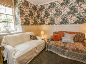 a living room with a couch and floral wallpaper at Trefoil Cottage in Biggar