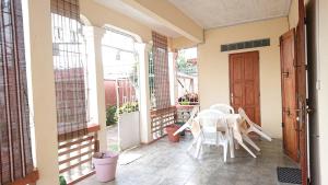 un patio con mesa y sillas en un porche en Chez Nofy Toamasina, en Toamasina