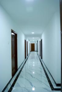 an empty corridor with white walls and marble floors at Paradise Golden Residency in Kottakupam