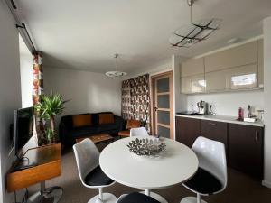 eine Küche und ein Wohnzimmer mit einem weißen Tisch und Stühlen in der Unterkunft Appartement - Galerie POP ART - Trentemoult in Rezé