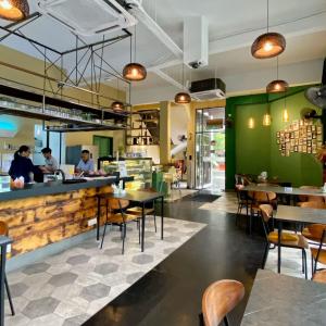 a restaurant with green walls and tables and chairs at Hotel Maluri in Kuala Lumpur