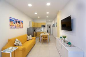 a living room with a yellow couch and a kitchen at KRIS Apartments in Giardini Naxos