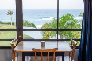 a table and chairs in front of a window with the ocean at 90 Eden Sands 2 Bedroom Flat with Beach Access in Kingsburgh