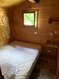 Ce lit se trouve dans une chambre en bois dotée d'une fenêtre. dans l'établissement les petits chalets de DUDU, à La Voulte-sur-Rhône