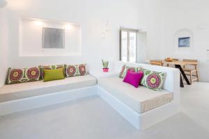 a white living room with two white couches with colorful pillows at Skyfall Suites - Adults Only in Pyrgos