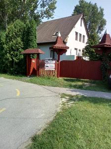 uma casa com uma cerca vermelha ao lado de uma rua em F 106 Vendégház em Fertőhomok