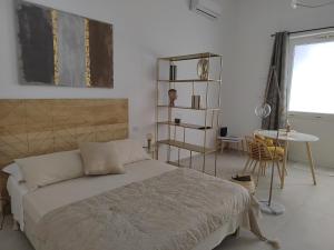 a bedroom with a bed and a table and a window at Dimore Gilas - Suite Golden in Monopoli +7 photos