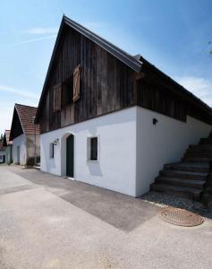 um grande edifício branco com um telhado de madeira e escadas em Weinkeller Röschitz em Roggendorf