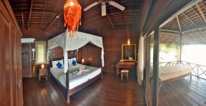 a bedroom with a bed and a desk in a room at Nunukan Island Resort in Maratua Atoll