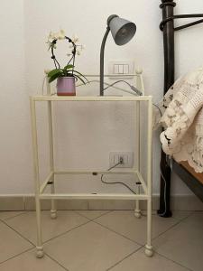 Appartamento Sa Benda في نوورو: طاولة جانبية بيضاء عليها مصباح وأزهار