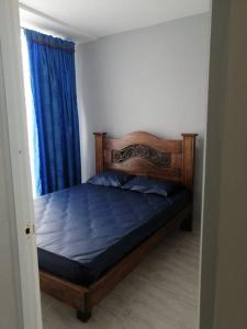 um quarto com uma cama com lençóis azuis e uma janela em Bellísima casa para descansar em Ricaurte