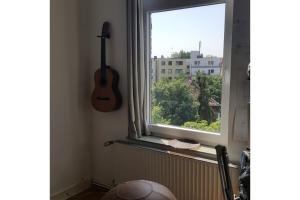 a guitar on the wall next to a window at Private Apartment in Hannover