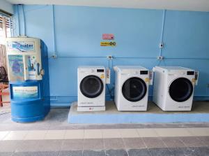 four washers and dryers are lined up in a room at Pa Chalermchai Guesthouse in Bangkok