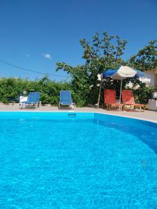 a blue swimming pool with two chairs and an umbrella at Creta Sun Hotel Studios in Agia Pelagia
