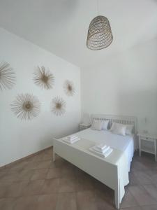 a white bedroom with a bed and three art installations on the wall at A'mmare Rooms&Apartments Santa Maria di Leuca in Leuca