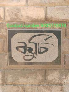 una señal en el costado de una pared de ladrillo en Kurchi Homestay, en Ghātsīla