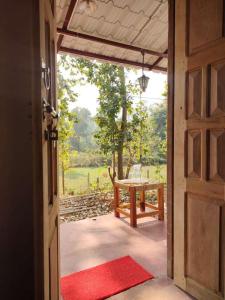 an open door leading to a patio with a table at Kurchi Homestay in Ghātsīla