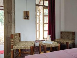 Ghātsīla的住宿－Kurchi Homestay，一间设有两把椅子、一张桌子和一个窗户的房间