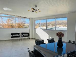 a dining room with a table and chairs and windows at Avis sunrise view in Windhoek
