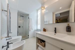 ein weißes Badezimmer mit einem Waschbecken und einem Spiegel in der Unterkunft ES Suites in Neapel