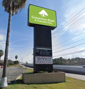 a green tree house sign on a pole next to a street at GreenTree Hotel & Extended Stay I-10 FWY Houston, Channelview, Baytown in Channelview