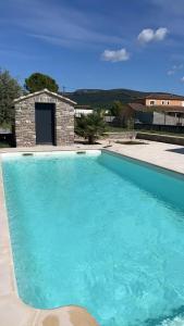 una gran piscina azul frente a una casa en Studio aux portes des Cévennes avec piscine en Moulès-et-Baucels
