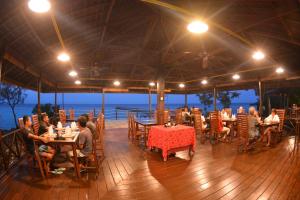 a group of people sitting at tables in a restaurant at Nunukan Island Resort in Maratua Atoll