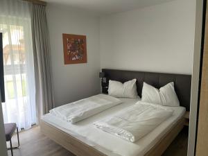 uma cama com lençóis brancos e almofadas num quarto em Ferienwohnung Siri Zentrum mit Garten em Sankt Michael im Lungau