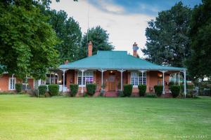 uma casa de tijolos vermelhos com um jardim verde em Old Rearsby em Mooirivier